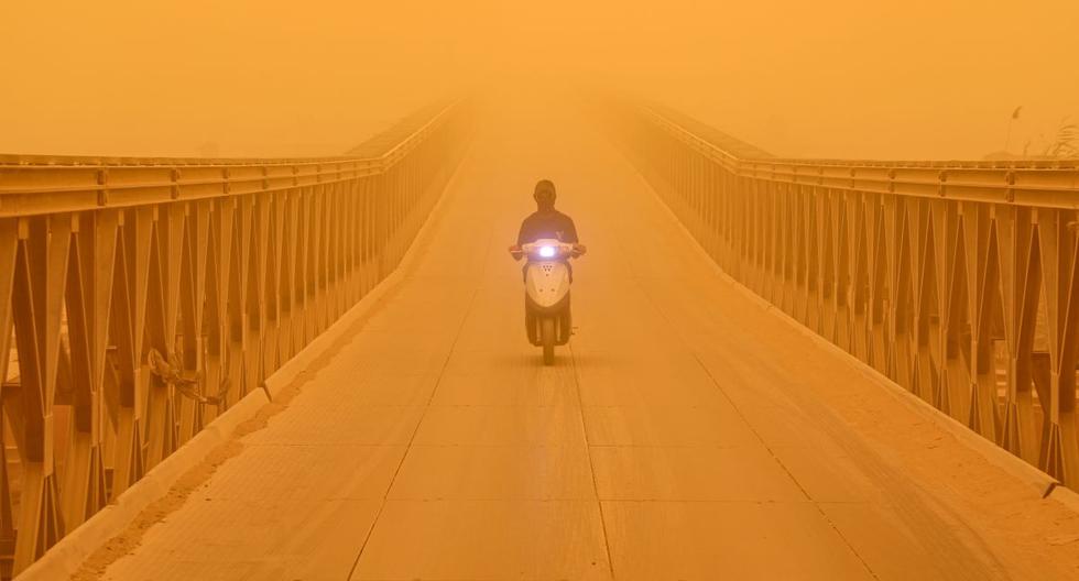Un motociclista conduce a lo largo de un puente en la ciudad de Nasiriyah, en la provincia de Dhi Qar, en el sur de Irak, el 16 de mayo de 2022 en medio de una fuerte tormenta de arena. (ASAAD NIAZI / AFP).