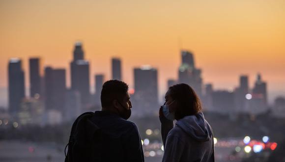 Una pareja que usa mascarillas para prevenir la propagación del coronavirus observa la puesta de sol desde Elysian Park en Los Ángeles, California, el 14 de noviembre de 2020. (Foto de Apu GOMES / AFP).