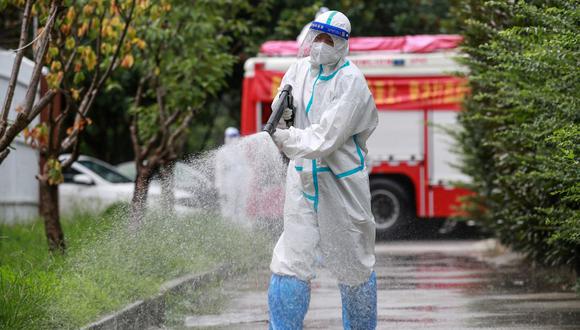 Un bombero con equipo de protección contra el coronavirus Covid-19 rocía desinfectante en un área residencial en Yangzhou, en la provincia de Jiangsu, en el este de China, el 11 de agosto de 2021. (Foto de STR / AFP).