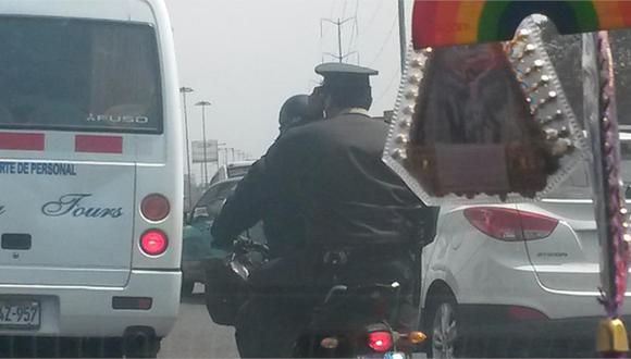 Policía sin casco habla por celular en una moto