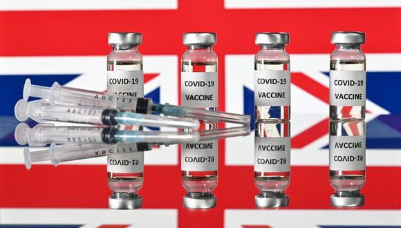 Una imagen ilustrativa muestra frascos con pegatinas de vacuna COVID-19 adjuntas y jeringas, con una bandera nacional del Reino Unido, el 17 de noviembre de 2020. (JUSTIN TALLIS / AFP).