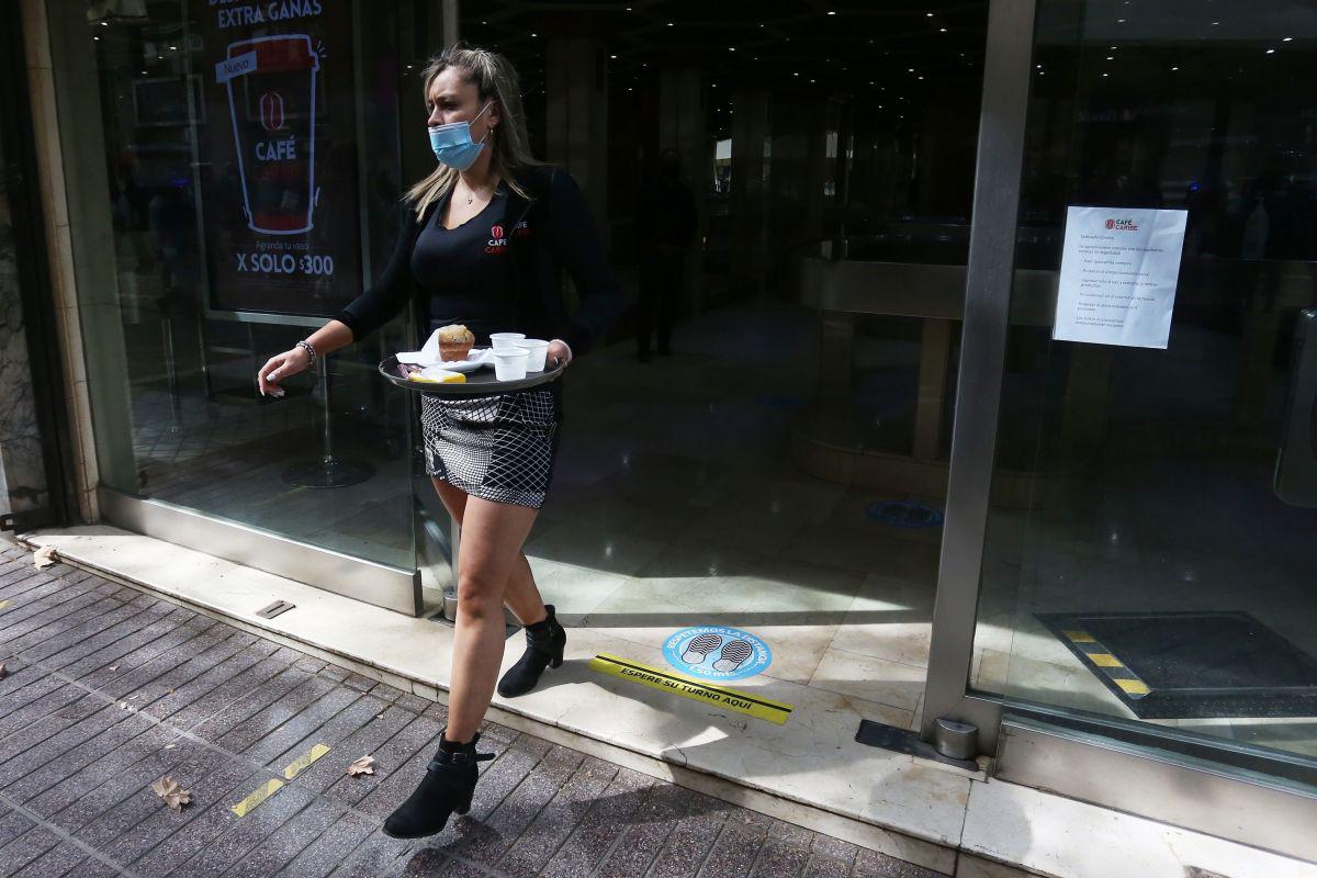 Una empleada de los llamados "café con piernas" trabaja durante la apertura de los negocios que no son de primera necesidad en el centro de Santiago de Chile. (EFE/Elvis González).