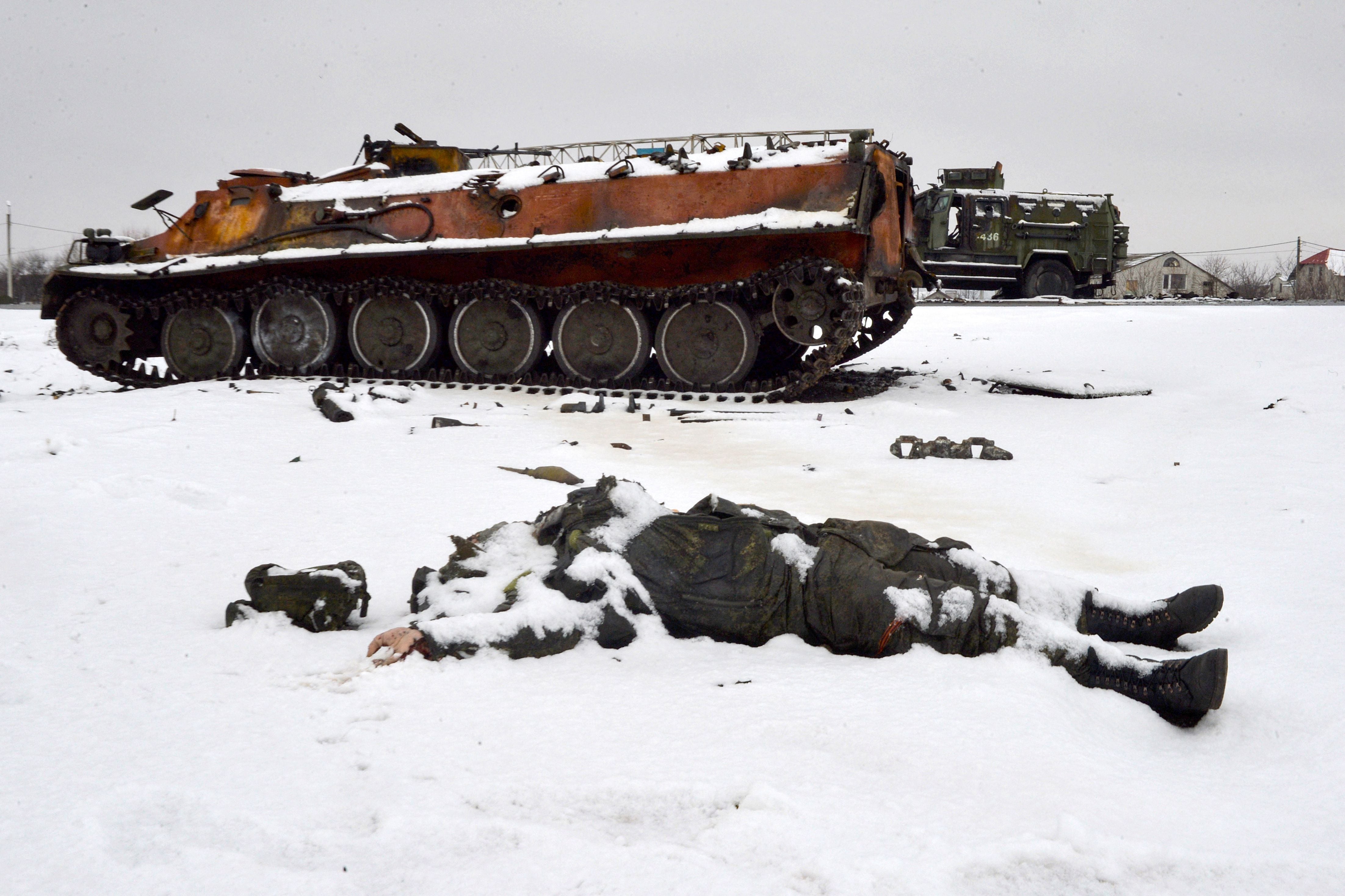 The body of a Russian soldier lies near destroyed Russian military vehicles on the side of a road on the outskirts of Kharkiv on February 26, 2022. (Photo by Sergey BOBOK/AFP).