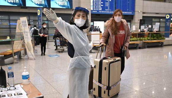 Una trabajadora guía a una viajera en la sala de llegadas del Aeropuerto Internacional de Incheon, en Corea del Sur, el 30 de noviembre de 2021, en medio de crecientes preocupaciones sobre la variante ómicron del coronavirus. (Jung Yeon-je / AFP).