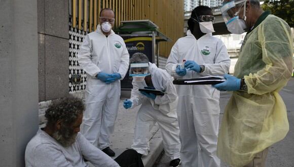 Trabajadores de Miami-Dade County Homeless Trust hablan con un hombre sin hogar antes de someterlo a pruebas de detección de la enfermedad por coronavirus en el centro de Miami, Florida. (Foto: AFP/Eva Marie Uzcategui)