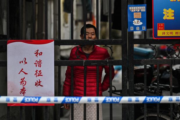 A resident of a Shanghai neighborhood is shown behind bars placed by authorities to control the movement of residents, who have been quarantined in some sectors of the city.  (AFP)