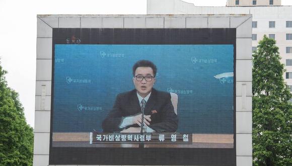 Una gran pantalla de video afuera de la estación de tren de Pyongyang muestra a Ryu Yong Chol, un funcionario de la sede estatal de prevención de epidemias de emergencia, hablando en Pyongyang el 27 de mayo de 2022. (Foto: KIM Won Jin / AFP)