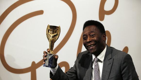 El exfutbolista brasileño Pelé sostiene una réplica del trofeo Jules Rimet, un trofeo otorgado al ganador de la Copa Mundial de fútbol, ​​durante una entrevista con los medios en una vista previa de una subasta de sus recuerdos en Londres.