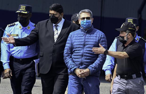 Juan Orlando Hernández es escoltado por el ministro de Seguridad, Ramón Sabillón (der), hacia un avión de la Agencia Antidrogas de Estados Unidos (DEA), durante su extradición a Estados Unidos, el 21 de abril de 2022. (Foto de Orlando SIERRA / AFP).