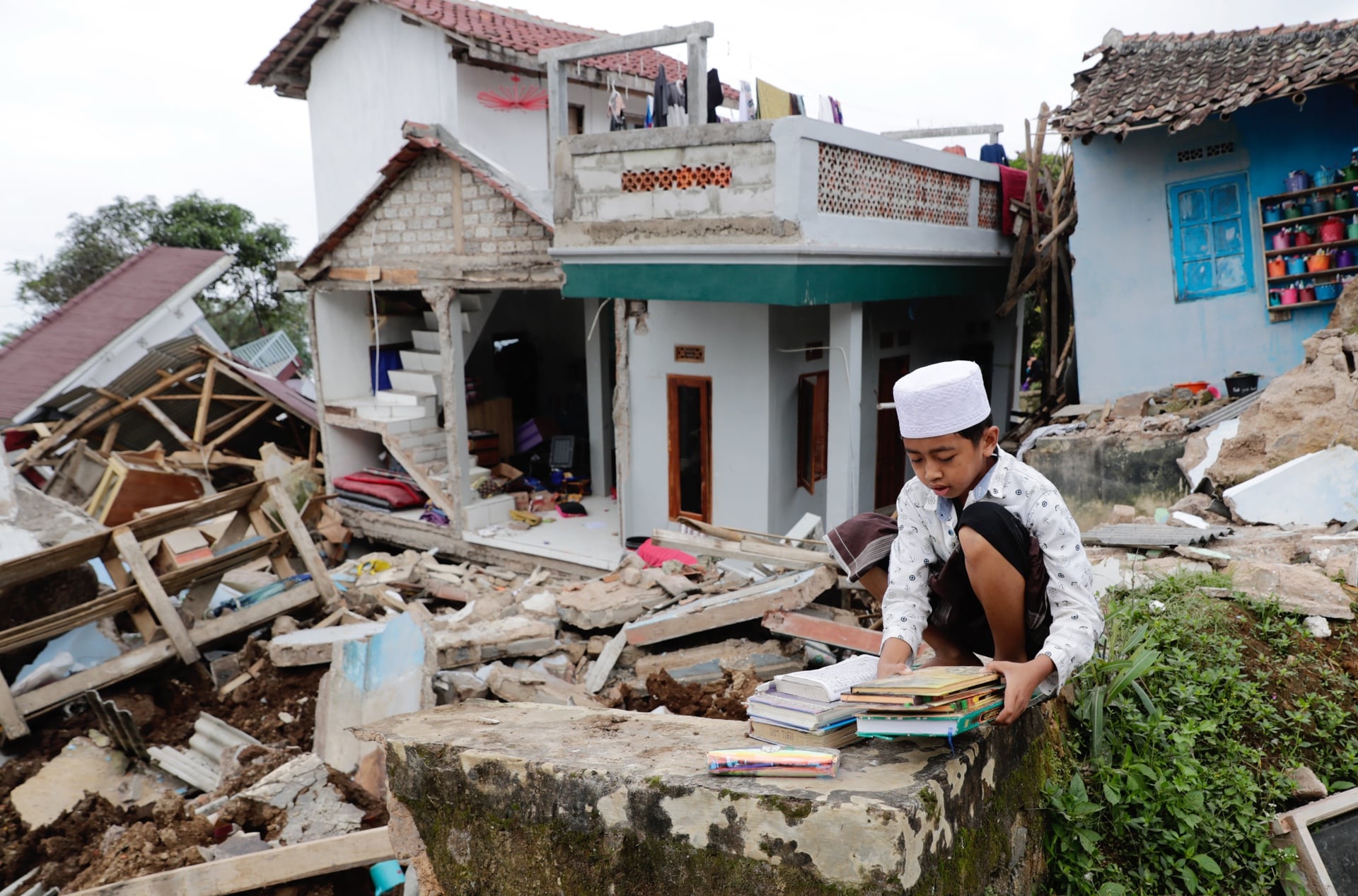 Un estudiante sostiene libros frente a su internado islámico colapsado a causa del terremoto en Cianjur, Indonesia, el 23 de noviembre de 2022. (EFE/EPA/ADI WEDA).