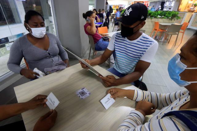 Unos clientes muestran su carnet de vacunación para obtener un descuento en el Restaurante Luigi, el 11 de agosto de 2021 en Cartagena de Indias (Colombia). (EFE/RICARDO MALDONADO ROZO).