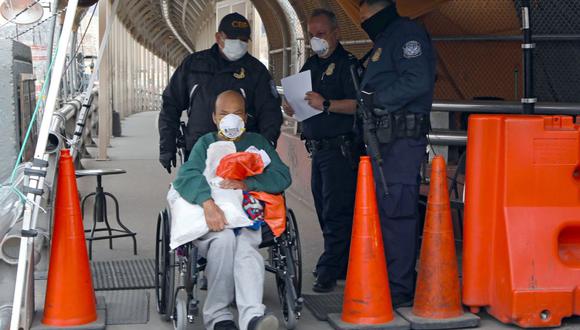 Agentes de la Oficina de Aduanas y Protección Fronteriza de los Estados Unidos empujan la silla de ruedas de un migrante mexicano mientras es deportado en el Puente Internacional Paso del Norte-Santa Fe en Ciudad Juárez, estado de Chihuahua (Foto: AFP)