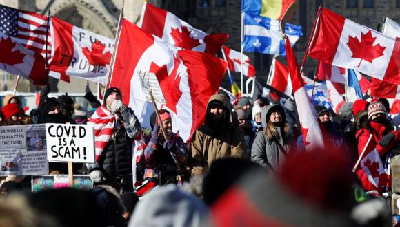 Los manifestantes sostienen banderas y carteles en Parliament Hill, mientras los camioneros y simpatizantes continúan protestando por los mandatos de vacunación contra la enfermedad por coronavirus (COVID-19), en Ottawa, Ontario, Canadá. (Foto: REUTERS/Lars Hagberg).