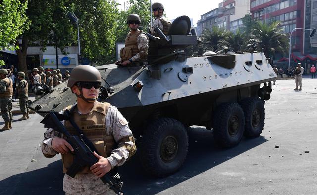 Los soldados del ejército chileno junto a una tanqueta de guerra patrullan las calles de Santiago de Chile. (AFP / Martin BERNETTI).