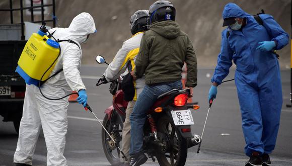 Empleados municipales desinfectan una motocicleta en Quito, Ecuador, el 31 de marzo de 2020, durante el brote del nuevo coronavirus. (Foto referencial, Rodrigo Buendía / AFP).