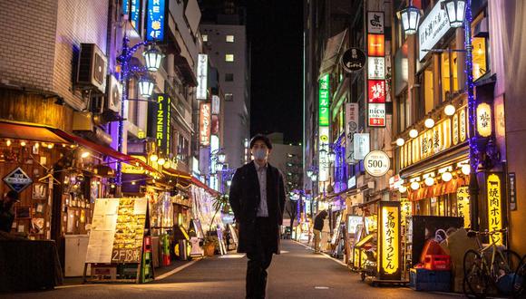 Un hombre camina por el área de restaurantes en el distrito Shinjuku de Tokio, Japón, el 21 de enero de 2022. (Felipe FONG / AFP).