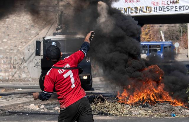 Un manifestantes lanza piedras a las fuerzas de seguridad de Santiago de Chile durante una protesta por falta de comida en plena cuarentena por coronavirus. (AFP / Martin BERNETTI).