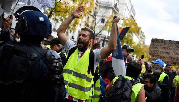 Un manifestante hace un gesto frente a la policía antidisturbios de CRS al comienzo de una manifestación contra el aumento del costo de vida y la inacción climática convocada por la coalición de izquierda francesa NUPES en París.