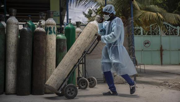 Un empleado de hospital transporta tanques de oxígeno en Puerto Príncipe, Haití, el 5 de junio del 2021. Desde el comienzo de la pandemia, Haití ha confundido a los expertos con tasas de infecciones y muertes bajas pese a su devastado sistema de salud, una ausencia total de vacunas y un desdeño casi total hacia las medidas de prevención como máscaras y distanciamiento. Pero un alza reciente de los casos está agobiando hospitales y causando preocupación. (AP Foto/Joseph Odelyn).