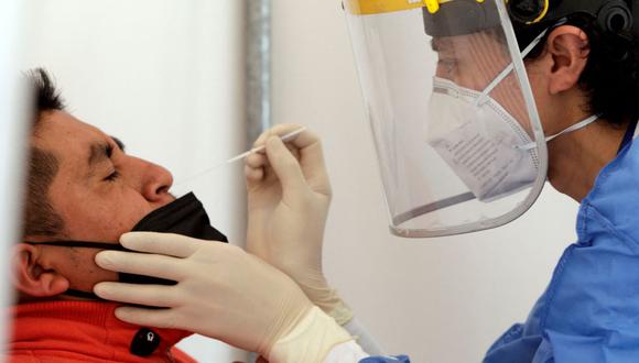 Un trabajador de salud toma una muestra nasal para una prueba de coronavirus COVID-19 de un hombre en una carpa en el Hospital General IESS Quito Sur, en Ecuador, el 4 de enero de 2022. (Cristina Vega RHOR / AFP).