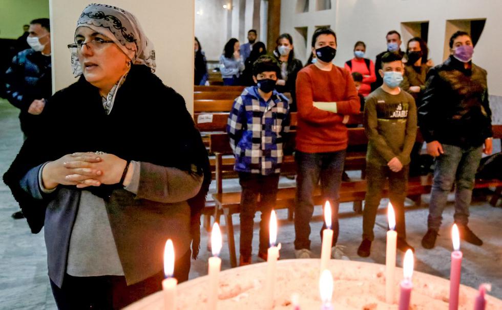 Dalia Yousef (izquierda), una refugiada cristiana iraquí-kurda de 42 años de Shaqlawa en el Kurdistán iraquí, reza ante las velas en la Iglesia Católica Romana de Santa María Madre de la Iglesia en Marka, al este de la capital de Jordania, el 13 de diciembre de 2020 , donde ha estado residiendo con su hijo Haval durante cinco años esperando la aprobación para emigrar a Australia. (Khalil MAZRAAWI / AFP)