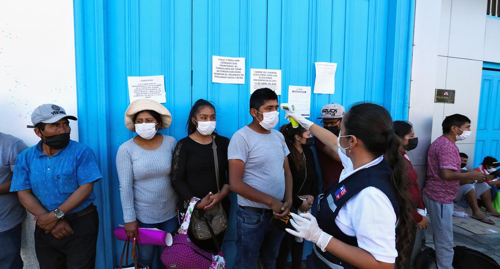 Los trabajadores de salud de Chile verifican la temperatura a las personas que se ubican en los exteriores del consulado peruano en la ciudad de Arica, el 23 de marzo de 2020. (AFP).