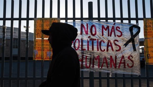 Un migrante pasa junto a un letrero que dice "No más políticas inhumanas" después de pasar la noche afuera del centro de detención migratoria donde 38 migrantes murieron durante un incendio en Ciudad Juárez, estado de Chihuahua, México el 29 de marzo de 2023. (Foto por Guillermo Arias / AFP)