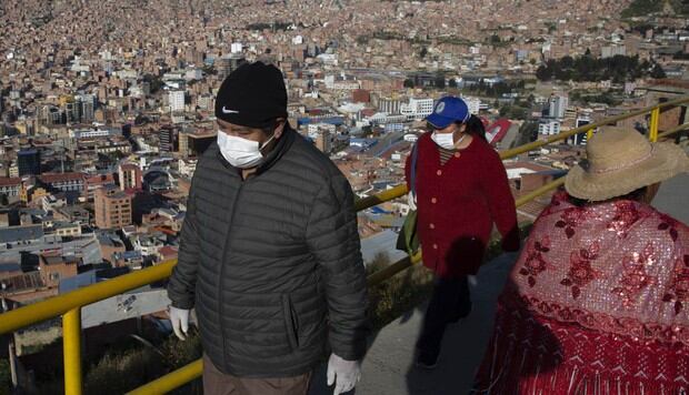 Las personas que usan máscaras faciales caminan hacia un mercado en La Paz. (AP/Juan Karita).