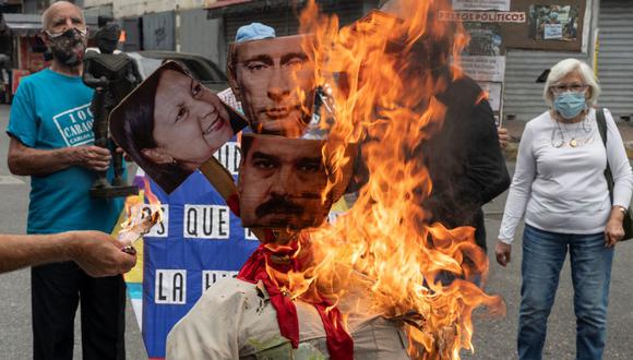 Opositores venezolanos queman un muñeco con las imágenes de Nicolás Maduro, Vladimir Putin y la alcaldesa de Caracas Carmen Meléndez. (YURI CORTEZ / AFP).