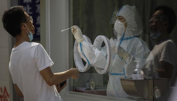 Imagen referencial del 14 de julio de 2020. Un trabajador médico con un equipo de protección completo examina a un hombre por la enfermedad del coronavirus en un hospital de China. (EFE/EPA/WU HONG).