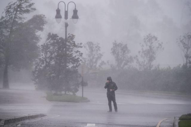 Un reportero se cubre la cara mientras informa sobre el impacto del huracán Delta en Lake Charles, Louisiana, el 9 de octubre de 2020. (Foto de CHANDAN KHANNA / AFP).