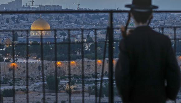 Un judío ultraortodoxo mira desde el Monte de los Olivos la Ciudad Vieja de Jerusalén, con una vista de la Cúpula de la Roca, en el recinto de la mezquita de al-Aqsa, el pasado 23 de septiembre de 2020. (AHMAD GHARABLI / AFP)
