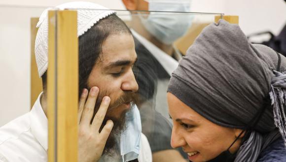 Amiram Ben-Uliel, un extremista judío condenado por el asesinato provocado por la Duma, habla con su esposa desde detrás de un cristal durante una audiencia de sentencia en el tribunal de distrito central de la ciudad central de Lod, en Israel, el 9 de junio de 2020. (Foto de MENAHEM KAHANA / AFP).
