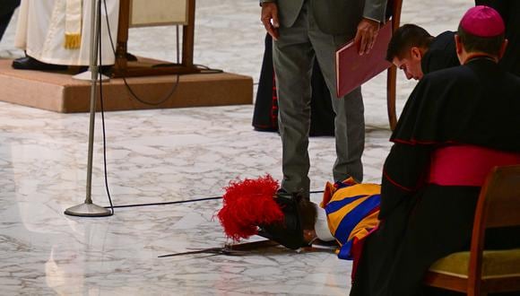 La gente atiende a un guardia suizo que yace en el piso después de que se desmayó durante la audiencia general semanal del Papa Francisco, el 17 de agosto de 2022 en la sala Paul-VI en el Vaticano. (Foto de Vincenzo PINTO / AFP)