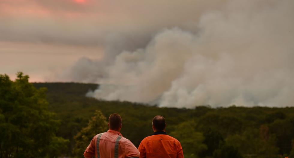 Dos residentes observan un gran incendio forestal visto desde Bargo, a 150 km al suroeste de Sydney. (AFP)