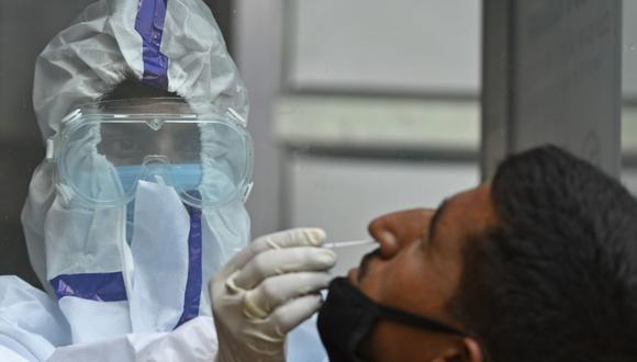 Un trabajador de la salud toma una muestra de un hisopo a un hombre para detectar el coronavirus COVID-19 en un centro de pruebas en Srinagar, India. (Foto: TAUSEEF MUSTAFA / AFP).