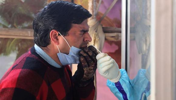 Un trabajador sanitario toma una muestra de un hisopo nasal de un hombre para realizar la prueba de coronavirus COVID-19 en un centro de pruebas en Srinagar, India. (EFE / EPA / FAROOQ KHAN).
