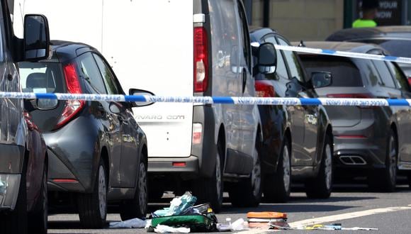 Un oficial de policía se encuentra junto a un cordón, cerca del equipo médico esparcido por Ilkeston Road en Nottingham, en el centro de Inglaterra, durante un "incidente importante" en el que tres personas fueron encontradas muertas. (Foto de Darren Staples/AFP)