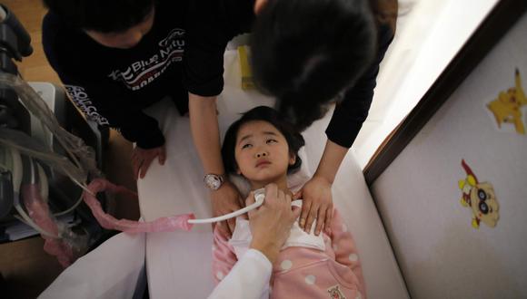 Un médico realiza un examen de tiroides a una niña de cinco años. (Foto referencial: Reuters)