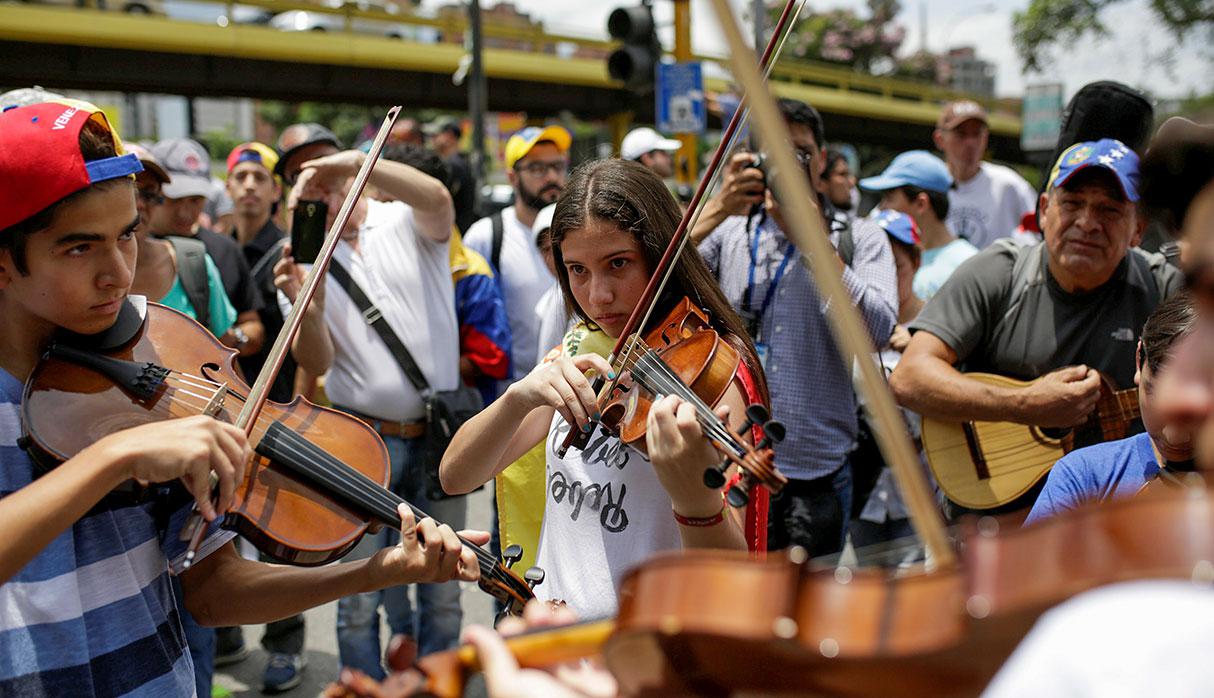 Young musicians play the violin during a gathering to pay homage to the victims of violence during the protest against Venezuela's President Nicolas Maduro's government in Caracas, Venezuela, May 7, 2017. REUTERS/Marco Bello