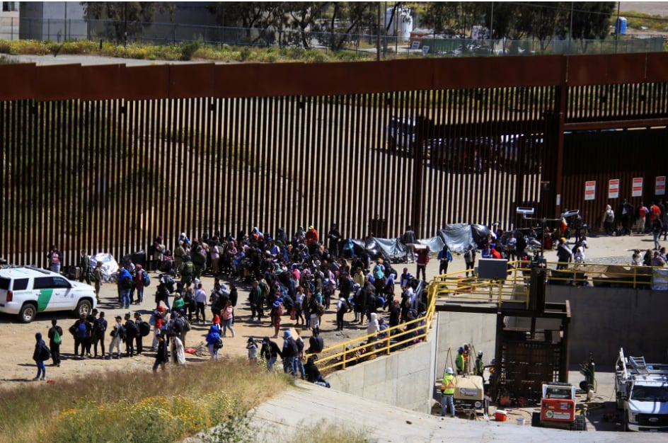 Migrants gather between the border fences in San Diego, California.. (REUTERS / Aimee Melo).