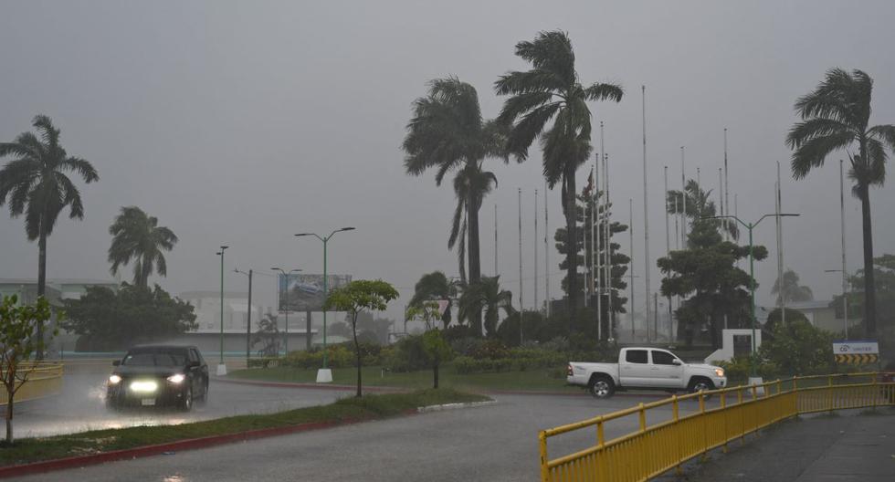 Los vehículos avanzan por una calle inundada debido a las fuertes lluvias antes de la llegada del huracán Lisa a Belice el 2 de noviembre de 2022. 
(Johan ORDÓNEZ / AFP).