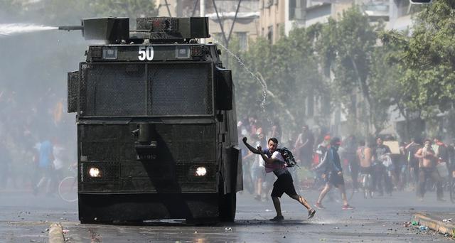 Una manifestante se acerca a un carro lanza agua de la policía durante una protesta en el centro de Santiago. (REUTERS/Ivan Alvarado).