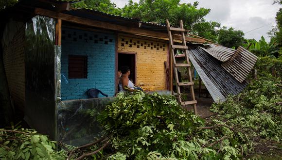 La gente se para en una casa con árboles caídos después de la tormenta tropical Bonnie, en Rivas, Nicaragua.