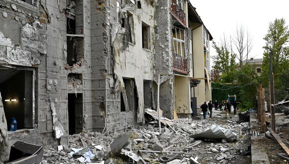 Los residentes locales se paran frente a su edificio parcialmente destruido por un ataque con misiles en Kharkiv el 12 de septiembre de 2022 en medio de la invasión rusa de Ucrania. (Foto de SERGEY BOBOK / AFP)