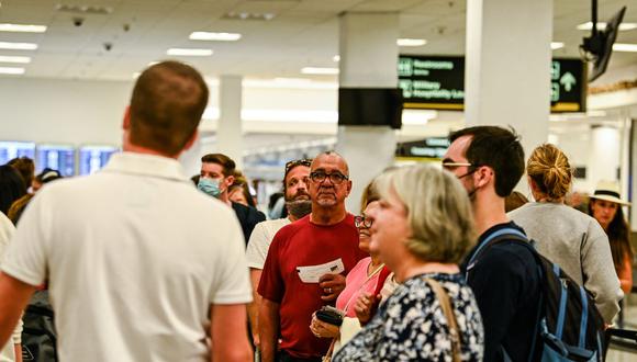 Los viajeros con y sin mascarilla hacen cola para el control de seguridad en el Aeropuerto Internacional de Miami, Estados Unidos, el 19 de abril de 2022. (CHANDAN KHANNA / AFP).