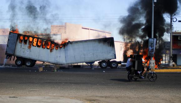 Hombres en motocicleta pasan junto a un camión en llamas en las calles de Culiacán, estado de Sinaloa.