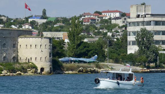 La gente disfruta de un paseo en barco por el Mar Negro frente a Sebastopol, la ciudad más grande de la Península de Crimea, el 16 de julio de 2022. La imagen muestra un avión. Foto: Olga MALTSEVA / AFP