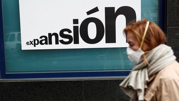 Una mujer con una mascarilla camina junto una sucursal bancaria de Madrid el lunes. (Foto: EFE)