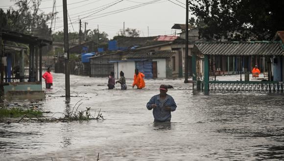 La gente camina por una calle inundada en Batabano, Cuba, el 27 de septiembre de 2022, durante el paso del huracán Ian. (Foto de YAMIL LAGE / AFP)